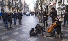 "En la acera opuesta de la calle, unos músicos callejeros forman una orquesta de cuerdas".